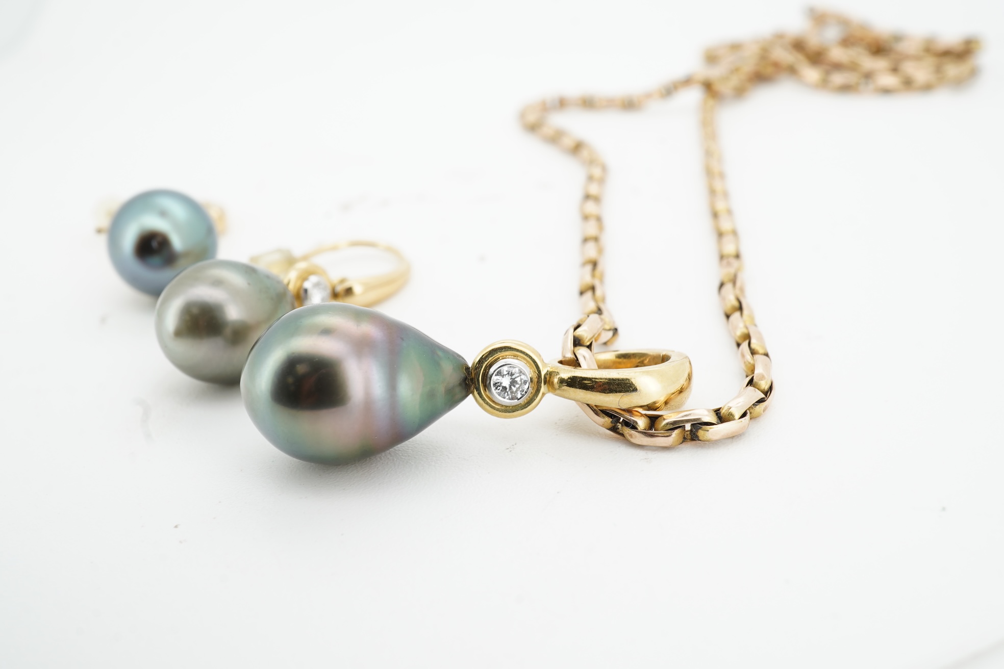 A cultured pearl and diamond demi-parure, comprising: a pendant, suspending a drop-shaped cultured pearl of black tint, measuring approximately 15 x 10.5 x 10.5mm, surmounted by a collet-set brilliant-cut diamond weighin